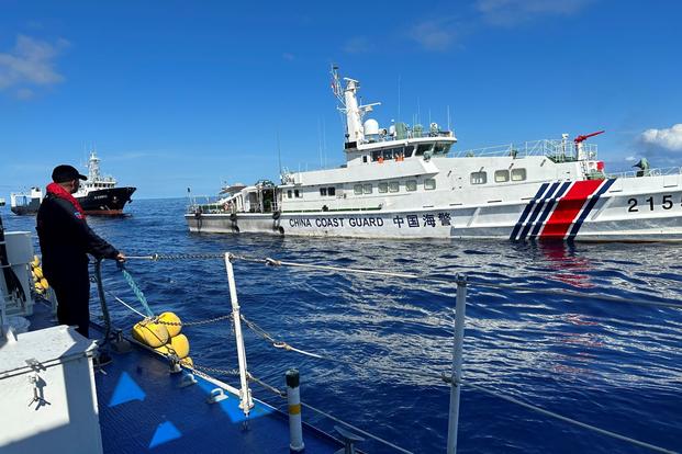 A Philippine Coast Guard member holds on a rubber fender as a Chinese coast guard vessel passes by. 