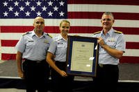 Coast Guard Petty Officer 2nd Class Sara Faulkner, receives recognition from Rear Admiral Bill Baumgartner, Commander of the 7th Coast Guard District and Capt. John Turner, commanding officer of Air Station Clearwater during an awards ceremony at Air Station Clearwater. (U.S. Coast Guard/Tara Molle)