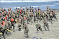 Basic Underwater Demolition/SEAL (BUD/S) candidates cover themselves in sand during surf passage on Naval Amphibious Base Coronado, California.