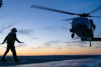 Sailor signals to an MH-60S Sea Hawk