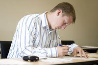 Man writing at a desk wearing a collared shirt.